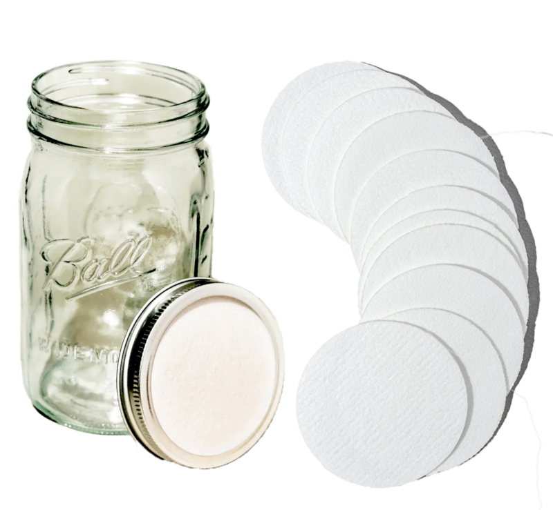 Jar lid filter discs next to a mason jar.