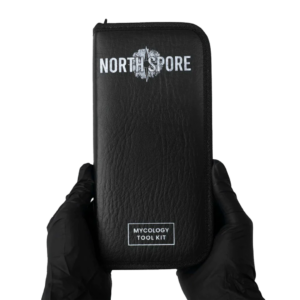 The rectangular leather pouch containing the mycology tool kit from north spore being held by someone wearing black nitrile gloves.